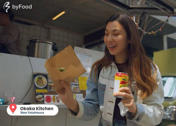 Shizuka smiling, having just purchased a bao bun and a can of apple cider at the Okaka Kitchen food truck.